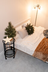 bedroom christmas decor. home interior for new years celebration. festive wreath, christmas tree. white sheets. pretty