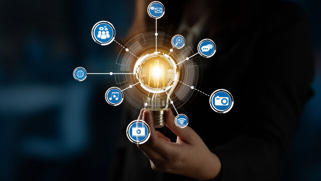 A professional woman displays a glowing light bulb, surrounded by various digital icons representing innovation, creativity, and effective communication in business contexts. Crux - Powered by Adobe