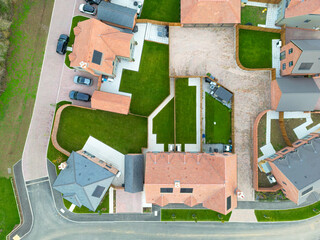 Drone inspection top down view of both detached a semi detached homes seen within a housing development project in rural Britain. Note the newly laid lush lawns.