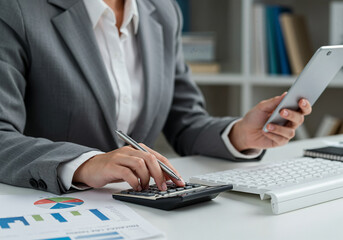 A woman is sitting at a desk with a laptop and a calculator. She is using the calculator to do some calculations.
