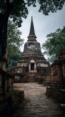 Fototapeta premium An ancient temple ruin in Thailand featuring a large stupa rising prominently in the scene. Weathered brick structures, aged stone textures, and surrounding greenery create a historic vibes