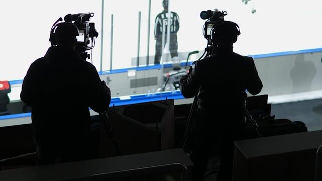 Professional TV cameramen filming ice hockey match broadcast at arena, live sports event transmission