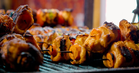 Sizzling chicken and vegetable skewers roasting over hot charcoal grill, releasing aromatic flavors in summer outdoor dining