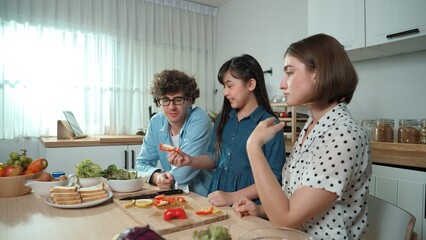 Happy father move to music while cooking food and prepare lunch at modern kitchen. Active dad dancing to song while making healthy food or salad surrounded with vegetable and kitchenware. Pedagogy.