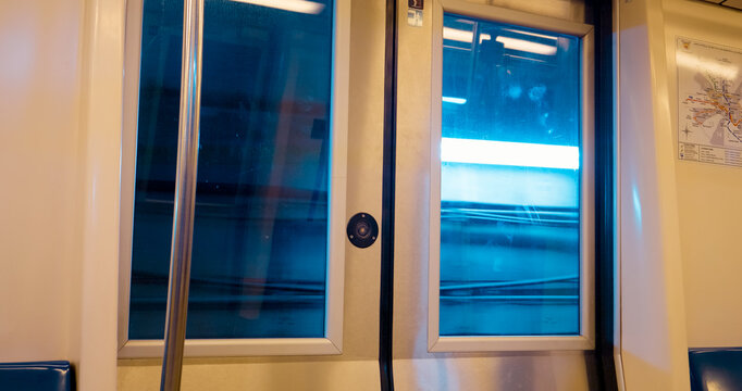 Reflection in the glass of a moving subway door captures the essence of urban travel as the train glides through the station amid the hustle