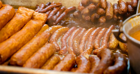 Delicious sausages sizzling on a hot plate, emitting fragrant steam in a bustling street food market