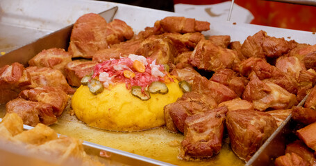 Traditional Romanian street food Tocana, a stew of pork meat and sausages, with polenta, pickles, served on a metal tray