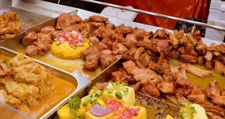 Romanian street food featuring grilled pork ribs, polenta, traditional sarmale, and colorful vegetables arranged on metal trays at local outdoor market stall