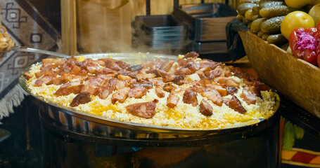 Delicious polenta with sausage and cheese and polenta steaming in a large pan at a street food market