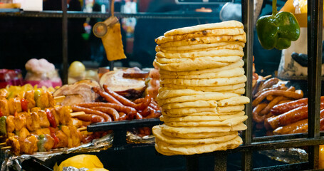 Sizzling grilled meat and pita bread at vibrant street market, revealing local culinary traditions through appetizing food preparation