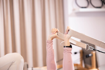 A close-up shot highlights focused hands gripping the straps of Pilates equipment, capturing the...