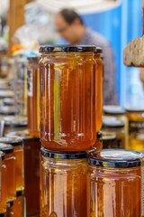 Glass jar of homemade honey at indoor market with food container on display.