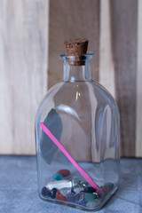 Gem stones or healing crystals in a square shaped glass jar that has a cork top.