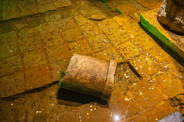 Ancient roman coins scattered in water near ruins