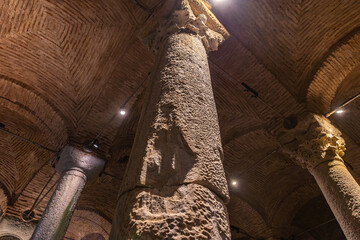 Ancient underground roman columns with intricate carvings and brick ceiling