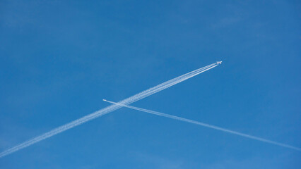 Dos aviones comerciales uno de cuatro motores y otro de dos cruzándose en un cielo azul