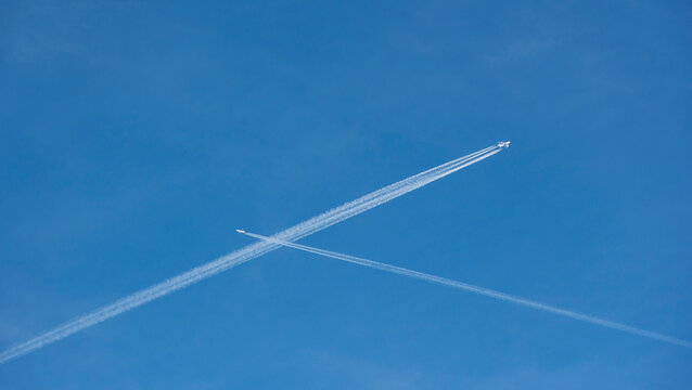 Dos aviones comerciales uno de cuatro motores y otro de dos cruz&aacute;ndose en un cielo azul