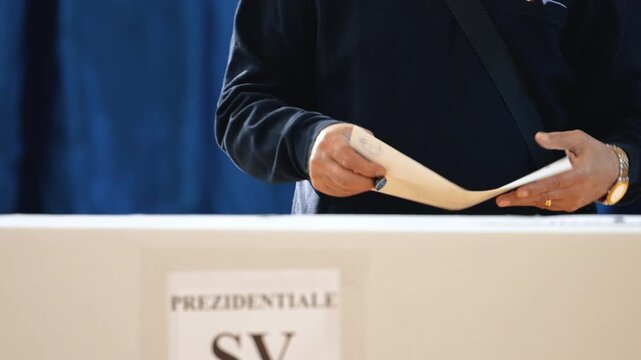 Close-up man holding ballot and stamp in front of ballot box, voting