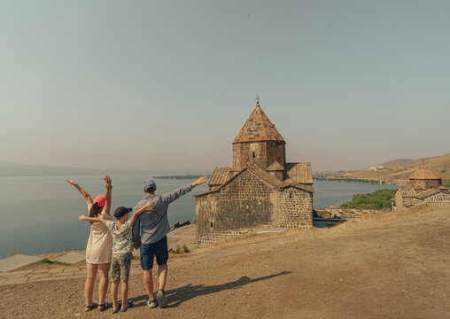 A family posing in front of the Sevanavank monastery complex and Lake Sevan in Armenia.