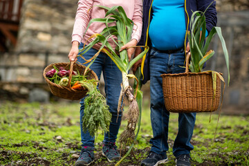 Couple holding fresh leeks and baskets of colorful vegetables