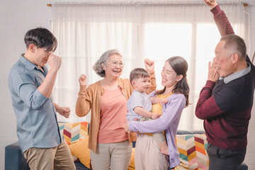 Happy Asian multigenerational family dancing and celebrating together at home, with joyful expressions and bonding moments, reflecting love, parenting, and vibrant family lifestyle.