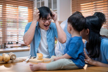 Fototapeta premium Asian father playfully entertains his toddler with a slice of bread in a cheerful kitchen setting. Fun family interaction capturing love, laughter, and warm bonding in modern parenting.