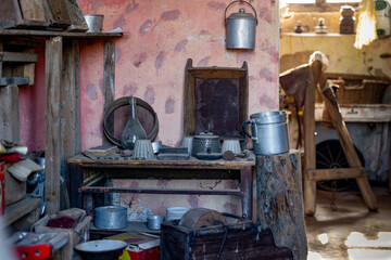 Vintage Kitchen Interior with Rustic Metal Cookware and Weathered Pink Wall in Traditional Old House