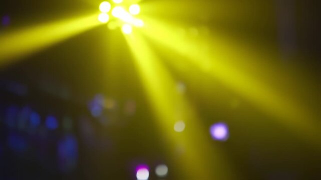 Radiant stage lights create a vibrant abstract composition with yellow rays and blue background