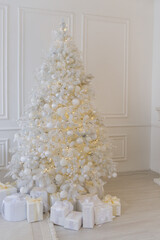 White Christmas interior with decorated tree, glowing garlands, candles, white gifts, elegant festive decor, and a round mirror above a white fireplace.