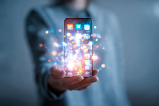 Person holding a futuristic transparent smartphone with glowing digital app icons and vibrant light effects symbolizing advanced technology and connectivity