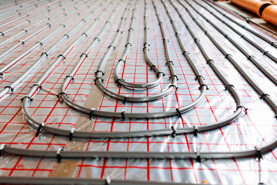 Radiant floor heating pipe installation in modern building,Close-up view of plastic pipes for radiant underfloor heating system installed on insulation layer, energy-efficient home construction.