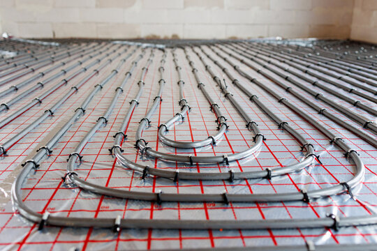 Radiant floor heating pipe installation in modern building,Close-up view of plastic pipes for radiant underfloor heating system installed on insulation layer, energy-efficient home construction.