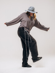 Female hip-hop dancer in gray street style outfit dancing in studio