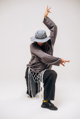 Female hip-hop dancer in gray street style outfit dancing in studio