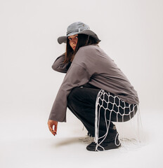 Female hip-hop dancer in gray street style outfit dancing in studio