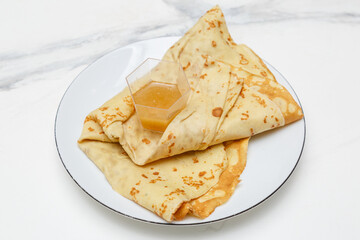 Crêpe au miel sur une assiette blanche, table en marbre, dessert français
