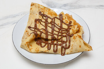 Cr&ecirc;pe au Nutella sur une assiette blanche, table en marbre, dessert fran&ccedil;ais