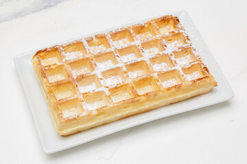 Gaufre nature sur une assiette blanche, table en marbre, dessert français