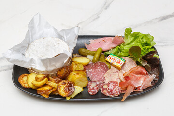 Fromage de Mont d’Or servi avec une planche de charcuterie et une salade, spécialité française