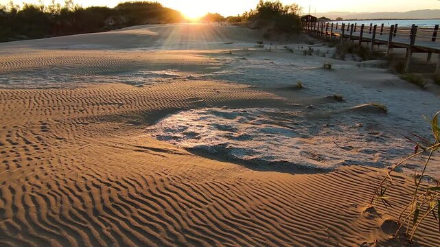 Panoramic view at sunset along a wooden boardwalk over the beach dunes.Track left,. Wooden walkways installed to protect the dunes and their flora and fauna, on Riumar beach in Catalonia, Spain