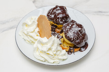 Profiteroles au chocolat garnies de chantilly sur une assiette, dessert français gourmand