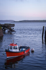 Fototapeta premium A red fishing boat moored at low tide in Cobh harbor, County Cork, Ireland.