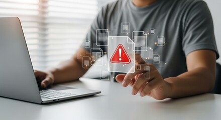 Male Asian user interacting with a laptop, focusing on a digital warning icon indicating a critical alert.