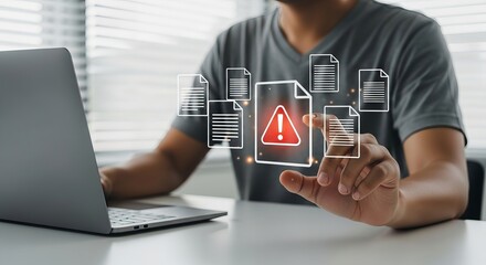 A young Asian man engages with digital document alerts while working on a laptop in a bright office setting.