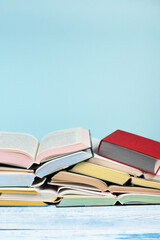 Open book, hardback colorful books on wooden table, blue background. Back to school. Copy space for text. Education business concept.