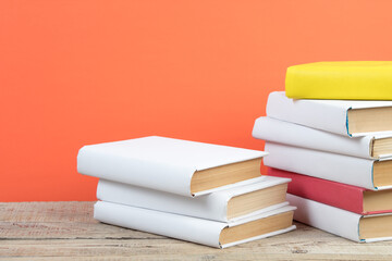 Books stacking. Books on wooden table and orange background. Back to school. Copy space for ad text.
