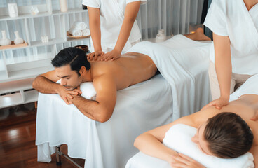 Fototapeta premium Caucasian couple customer enjoying relaxing anti-stress spa massage and pampering with beauty skin recreation leisure in day light ambient salon spa at luxury resort or hotel. Quiescent