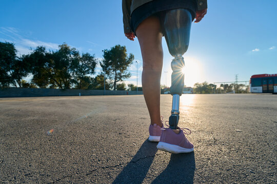Woman with prosthetic leg walking outdoors at sunset - Powered by Adobe