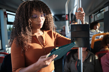Woman commuting on public transport checking tablet