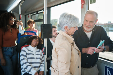 Senior man showing smartphone to woman on bus